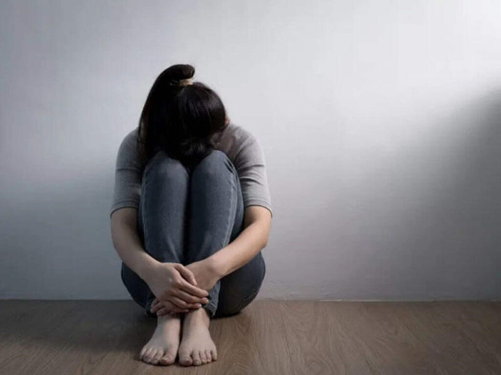 pessoa triste, sentada e de cabeça baixa
